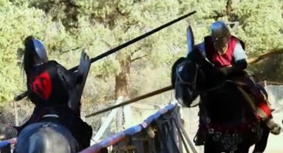 Two men on horses jousting.