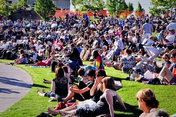 Outdoor concert with people sitting on grass.
