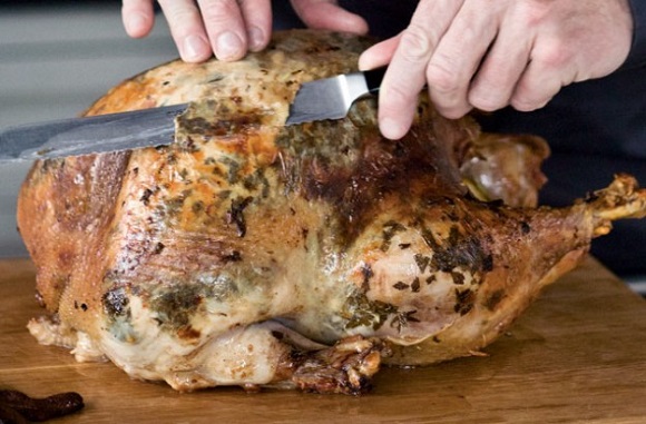 Turkey cut with knife as two hands hold it.
